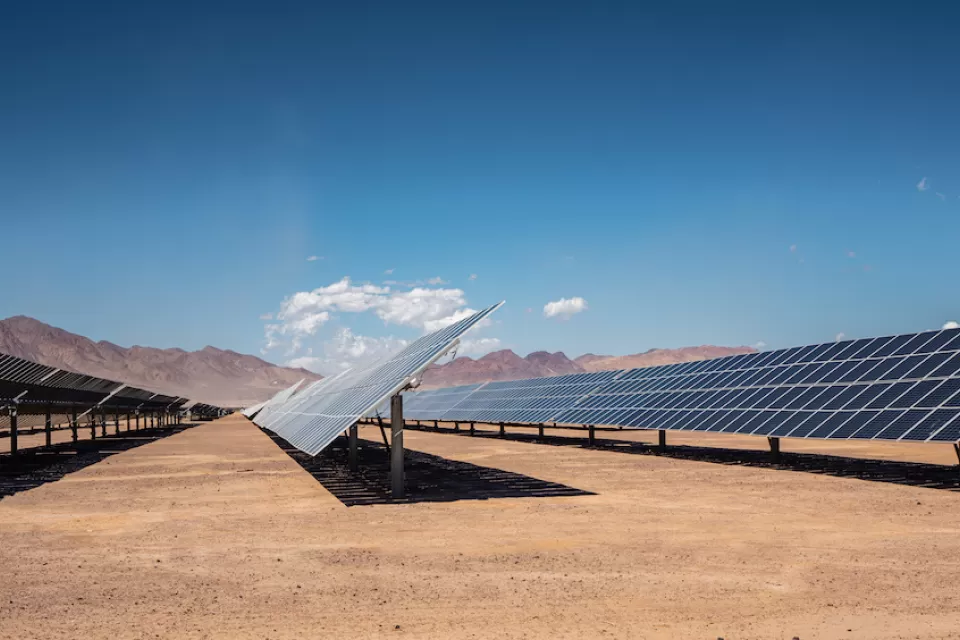 Rows of photovoltaic solar panels in the Nevada desert with mountains in background.